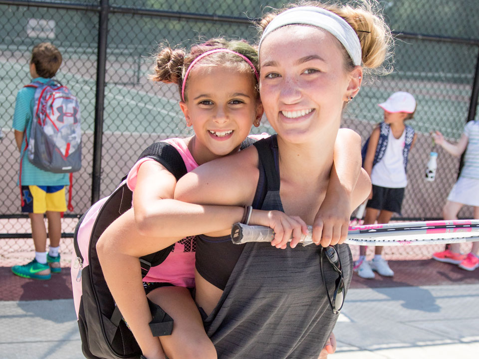 Girls Tennis Camp Counselor giving a piggyback ride